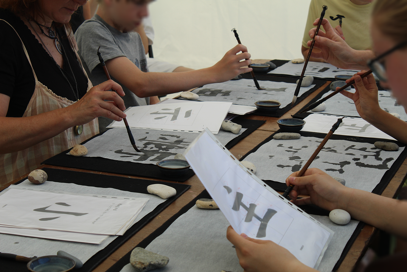Cours de calligraphie japonaise intergénérationnel réunissant enfants, adultes et seniors à l'AMCJ